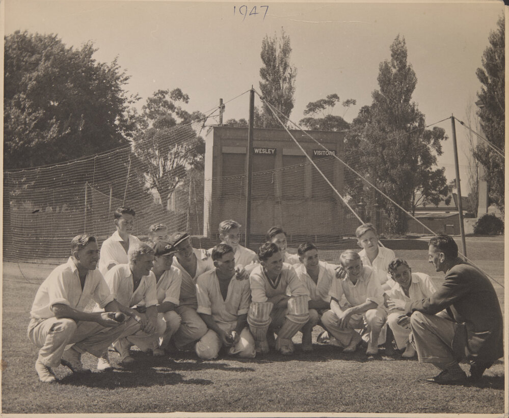 Cricket XI 1947 crouching against the nets